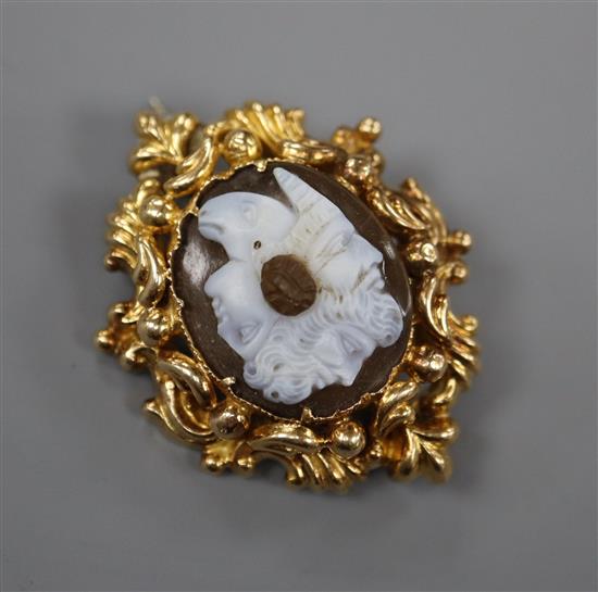 A Victorian yellow metal mounted chalcedony cameo brooch, the carving incorporating three classical faces and a rams head, 35mm.